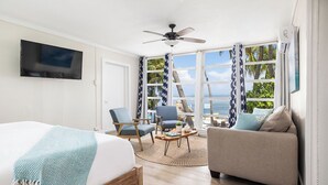 A bedroom with a bed, two chairs, a sofa, a TV, and a large window with a view of the ocean. - La Jolla Resort (Islamorada)