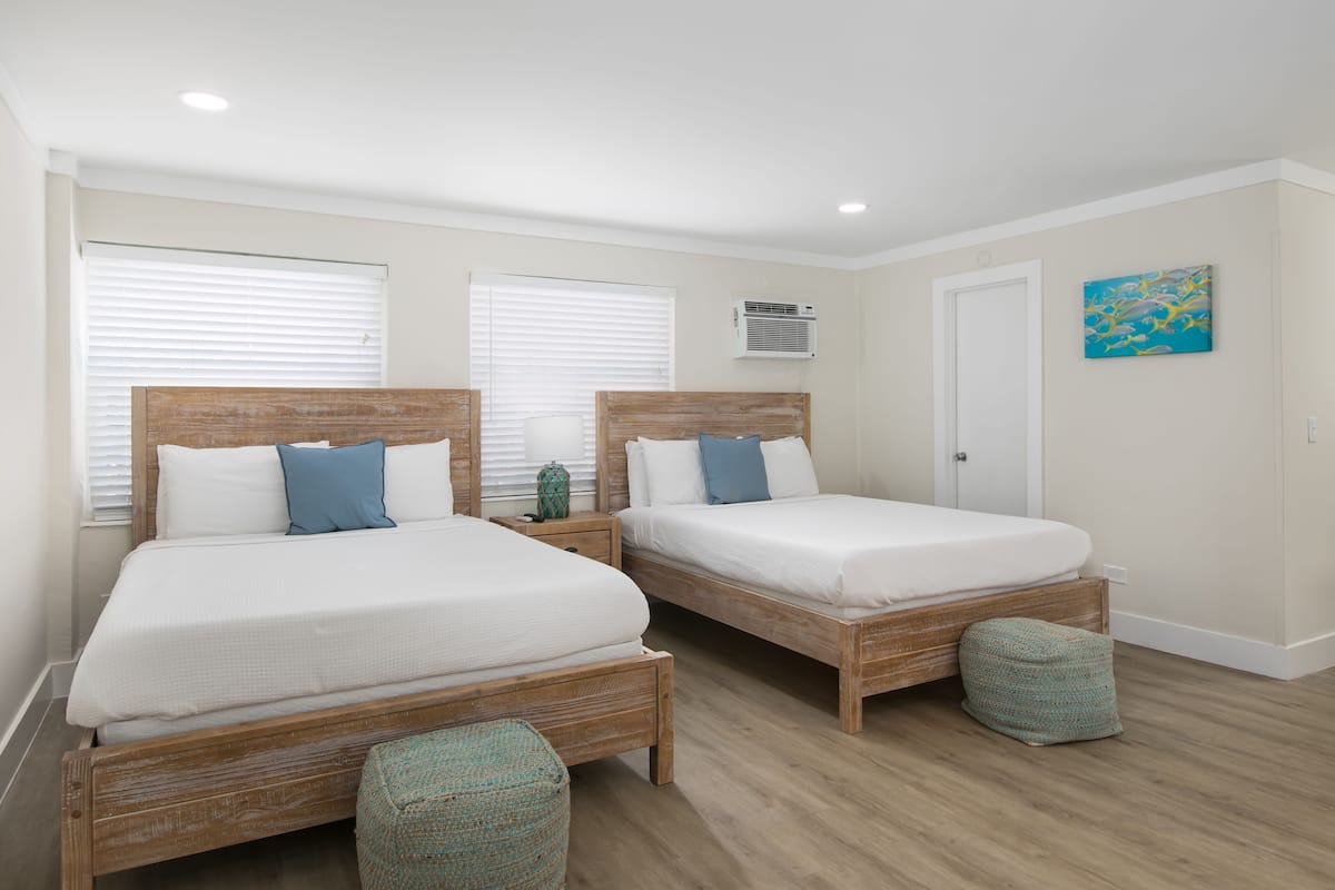 A bedroom with two wooden beds, white bedding, and a small green decorative item on the nightstand.