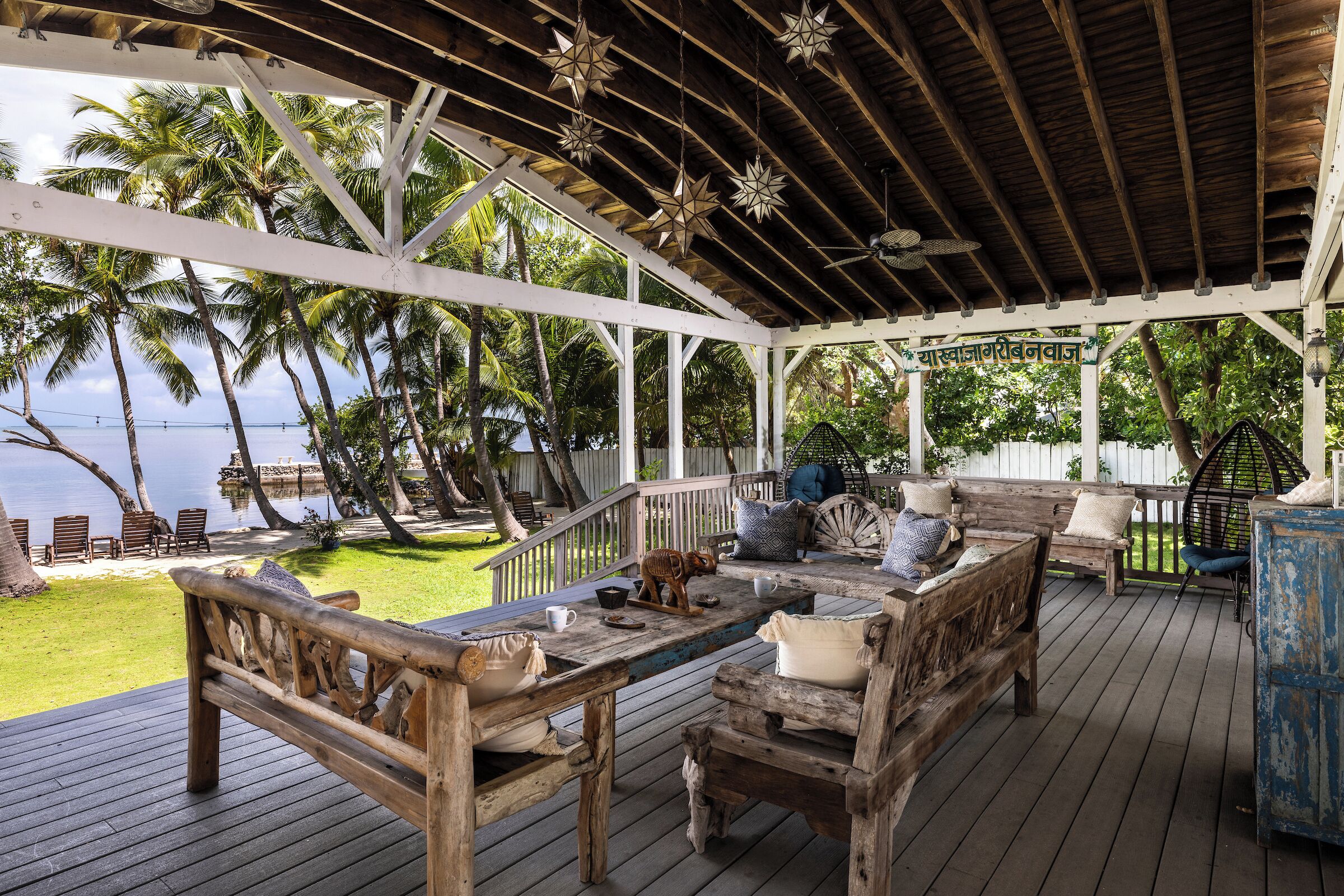 Une terrasse en bois avec des meubles d’extérieur, une pergola et une vue sur l’océan.
