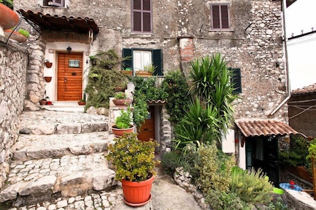 A stone building with a wooden door, potted plants, and a small garden area.