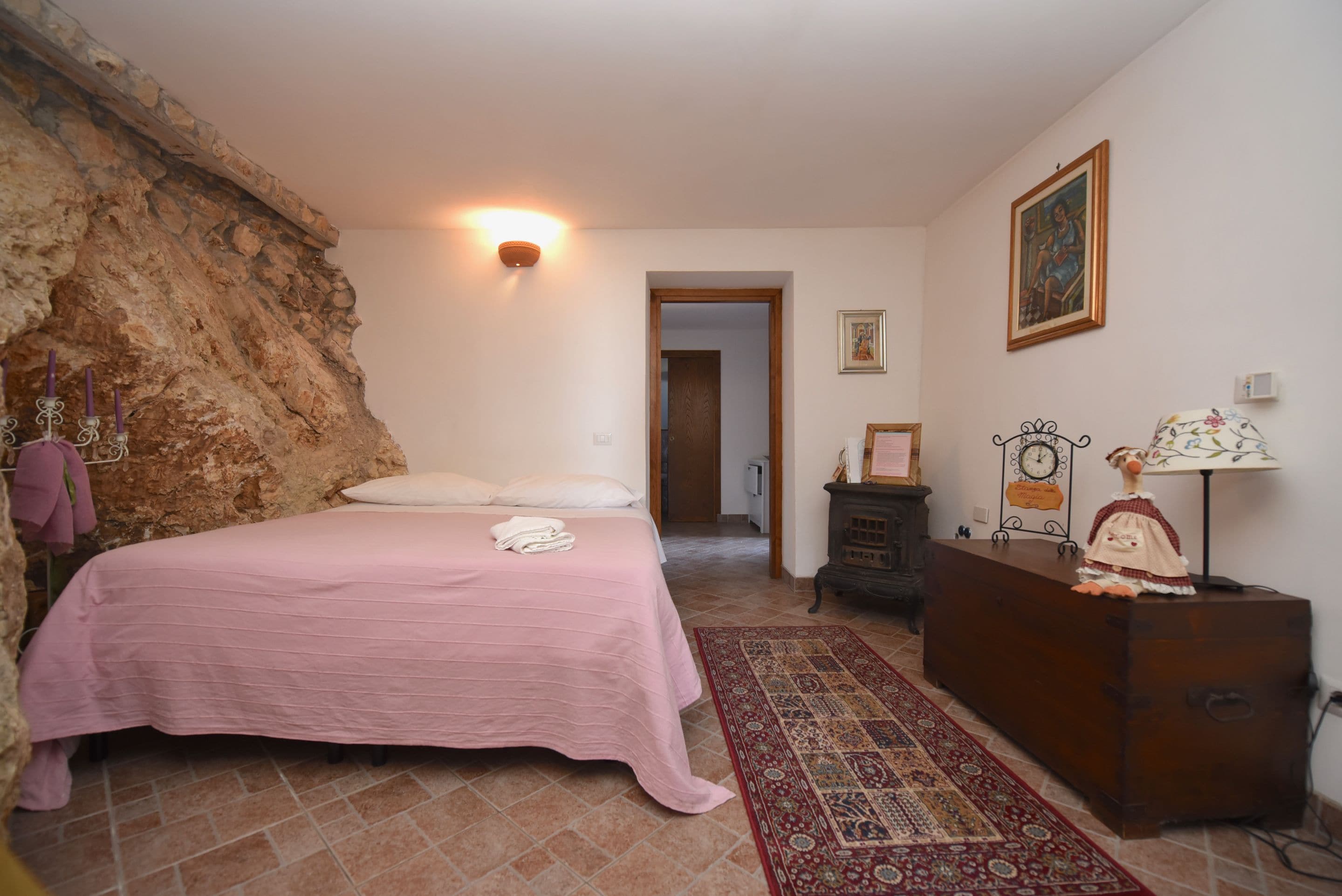 A bedroom with a bed, a dresser, a wall-mounted clock, and a door leading to another room.