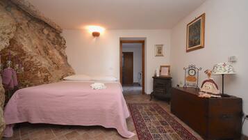 A bedroom with a bed, a dresser, a wall-mounted clock, and a door leading to another room.