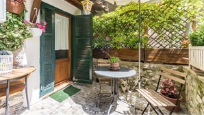 Un patio exterior acogedor con una mesa de madera, un banco y plantas en macetas.