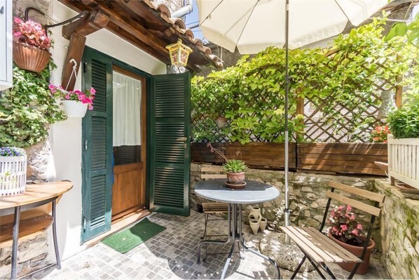 Un patio exterior acogedor con una mesa de madera, un banco y plantas en macetas.