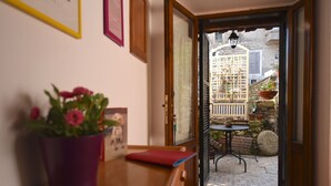 Una puerta que da a un patio exterior con una mesa, sillas y plantas en macetas.