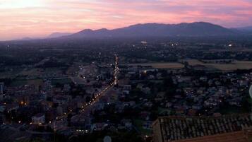 Une vue panoramique d’une ville au crépuscule, traversée par une rivière et entourée de montagnes.