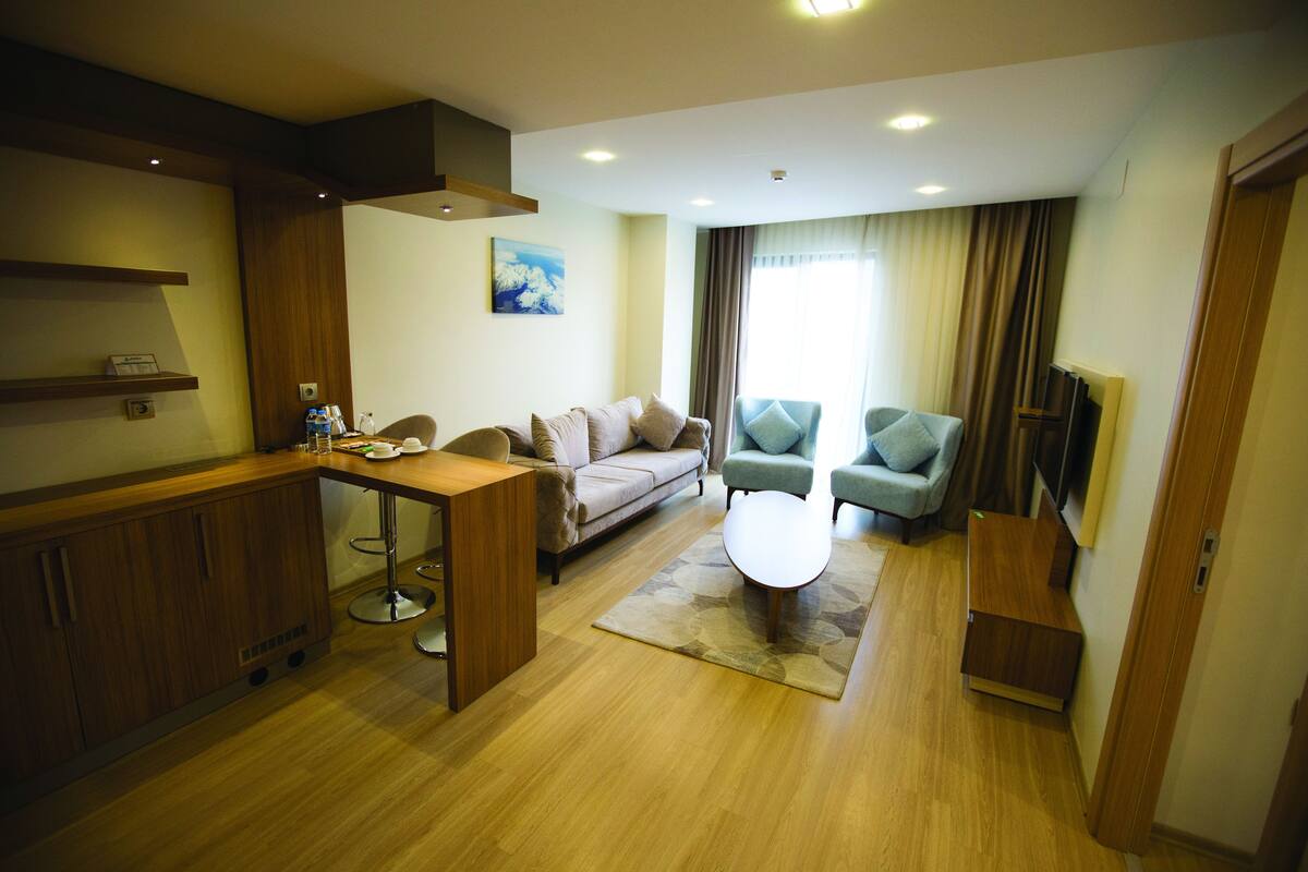 A modern living room with a sofa, two armchairs, a coffee table, and a TV.
