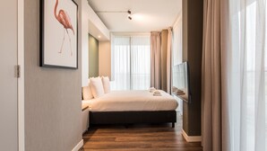 A modern hotel room with a large bed, a TV, and a window with curtains. - YAYS Amsterdam North by Numa (Amsterdam)