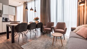 A modern living room with a sofa, armchairs, a dining table with chairs, and a kitchen area. - YAYS Amsterdam North by Numa (Amsterdam)