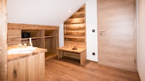 Een moderne keuken met houten kastjes, een geïntegreerde wijnkoeler en een klein houten tafeltje met een schaal en appels.