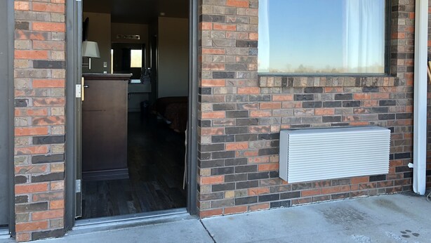 A hotel room with a brick exterior, a sliding glass door, a window with a view, and a built-in heater. - Rosener's Inn and banquet center (Park Hills)