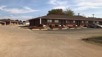 A motel with a parking lot, a brick building, and a few cars parked.