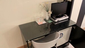 A compact workspace with a black desk, a white chair, a small refrigerator, and a vase with flowers. - Basic Confort 2 (San Sebastián)