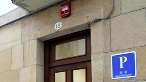 A stone building with a wooden door, a blue parking sign, and a fire alarm. - Basic Confort 2 (San Sebastián)