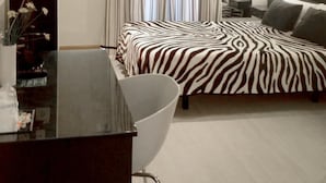 A modern hotel room with a zebra-patterned bed, a white chair, a desk with a vase of flowers, and a striped wall. - Basic Confort 2 (San Sebastián)