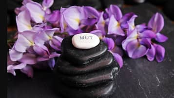 Une pierre noire sur laquelle est apposée une étiquette blanche portant l’inscription « MUT », le tout entouré de fleurs violettes.