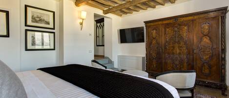 Un dormitorio con una cama, un armario de madera, un televisor y cuadros en la pared.