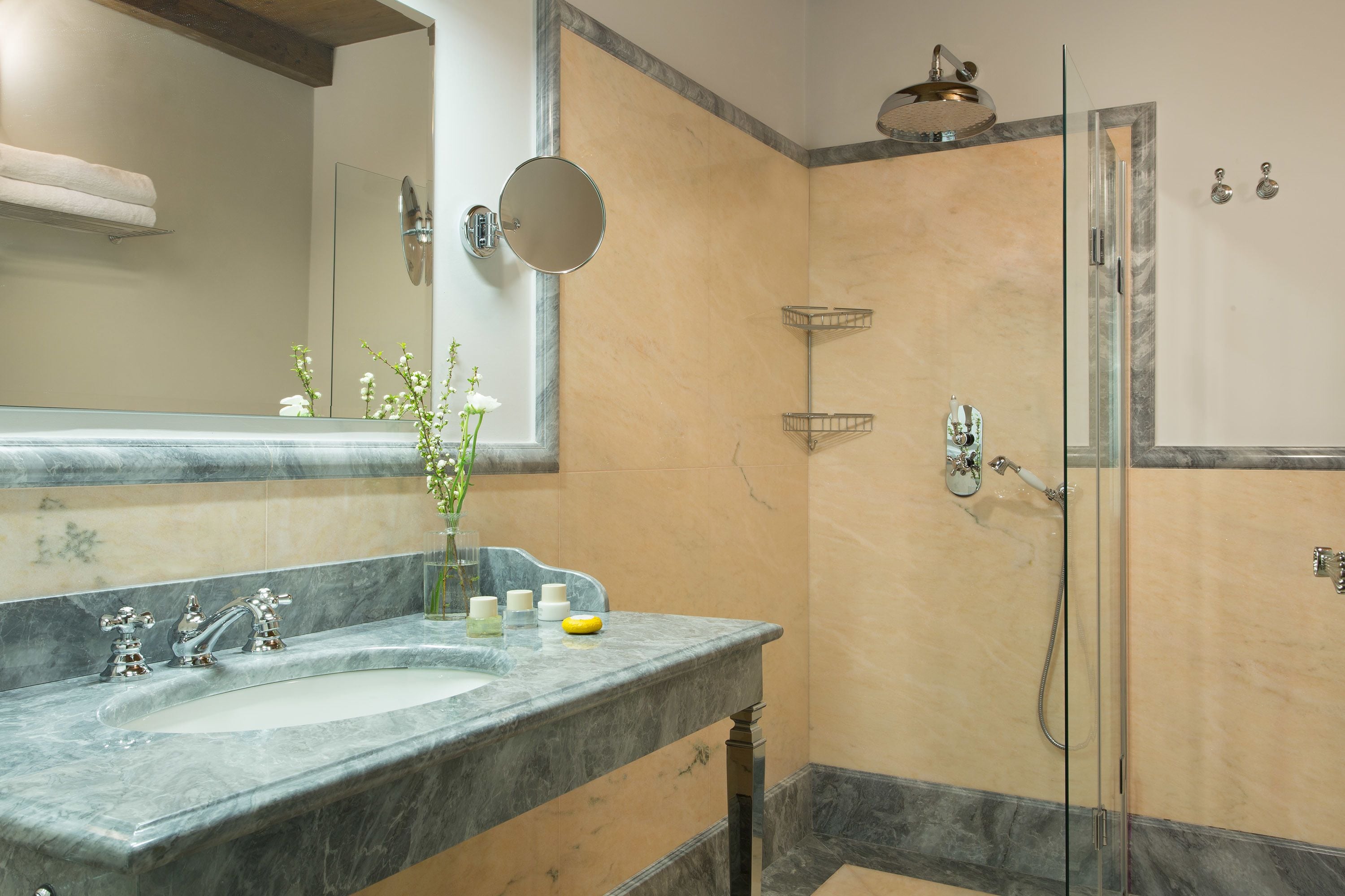 A bathroom with a marble sink, a glass shower enclosure, and a mirror.