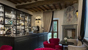 Un espace bar avec un comptoir sombre, des chaises rouges et une cheminée.
