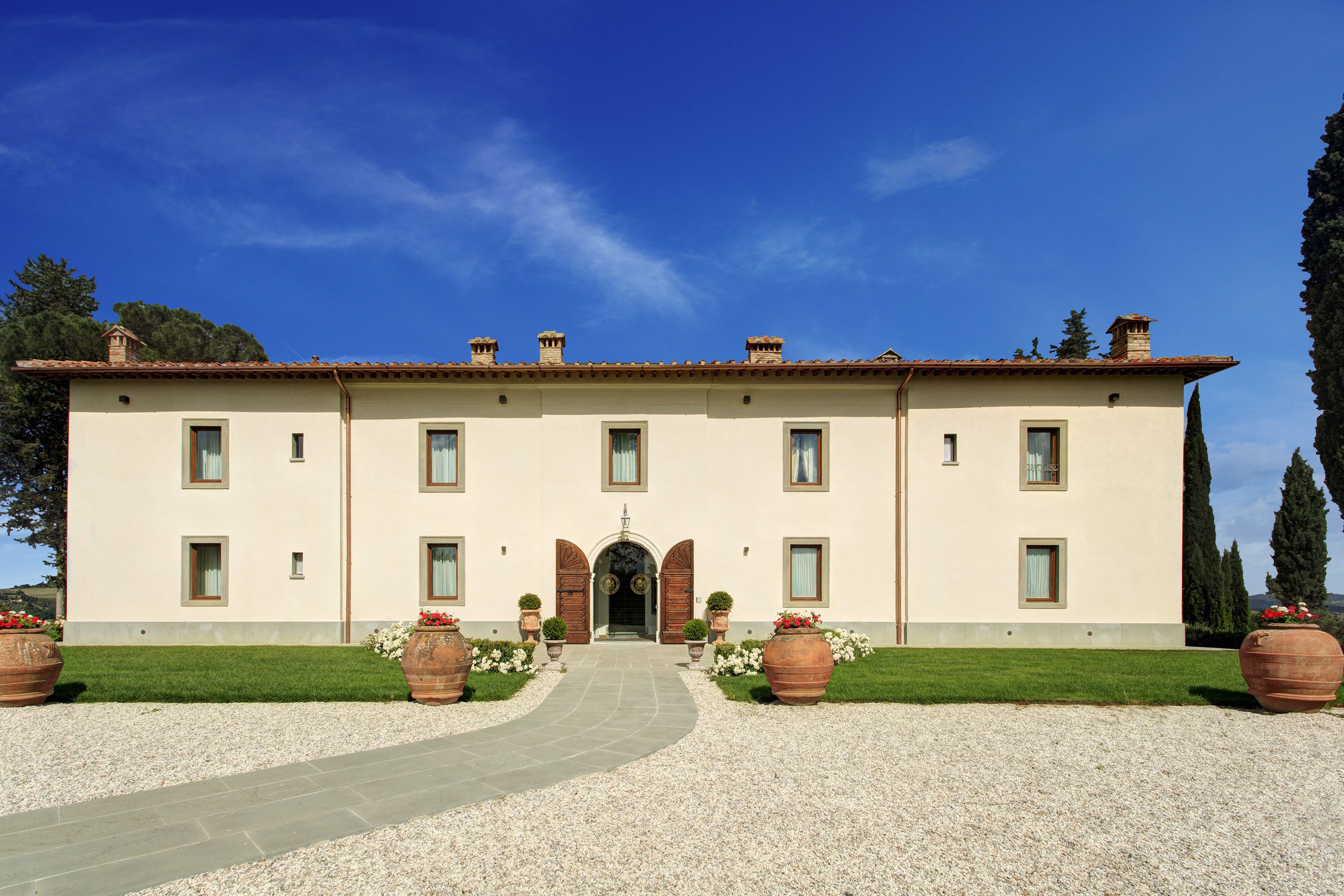 Un edificio grande su due piani, con una facciata simmetrica, un ingresso centrale ad arco e finestre regolarmente distanziate.