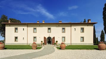 Un edificio grande su due piani, con una facciata simmetrica, un ingresso centrale ad arco e finestre regolarmente distanziate.