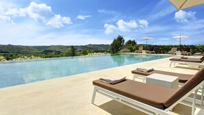 Un espace aménagé au bord de la piscine, avec des chaises longues et des parasols, offrant une vue sur un paysage pittoresque.
