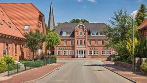A red-brick building with a clock tower, a sign reading "Hotel," and a street in front. - Hotel Hollenstedter Hof (Hollenstedt)