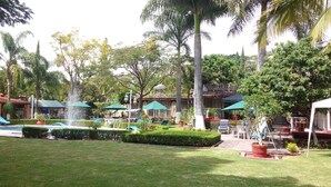 A resort with a swimming pool, outdoor seating, and lush greenery. - Villa Paraiso (Emiliano Zapata)