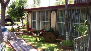 A garden with a paved walkway, potted plants, and a wooden bench. - Villa Paraiso (Emiliano Zapata)