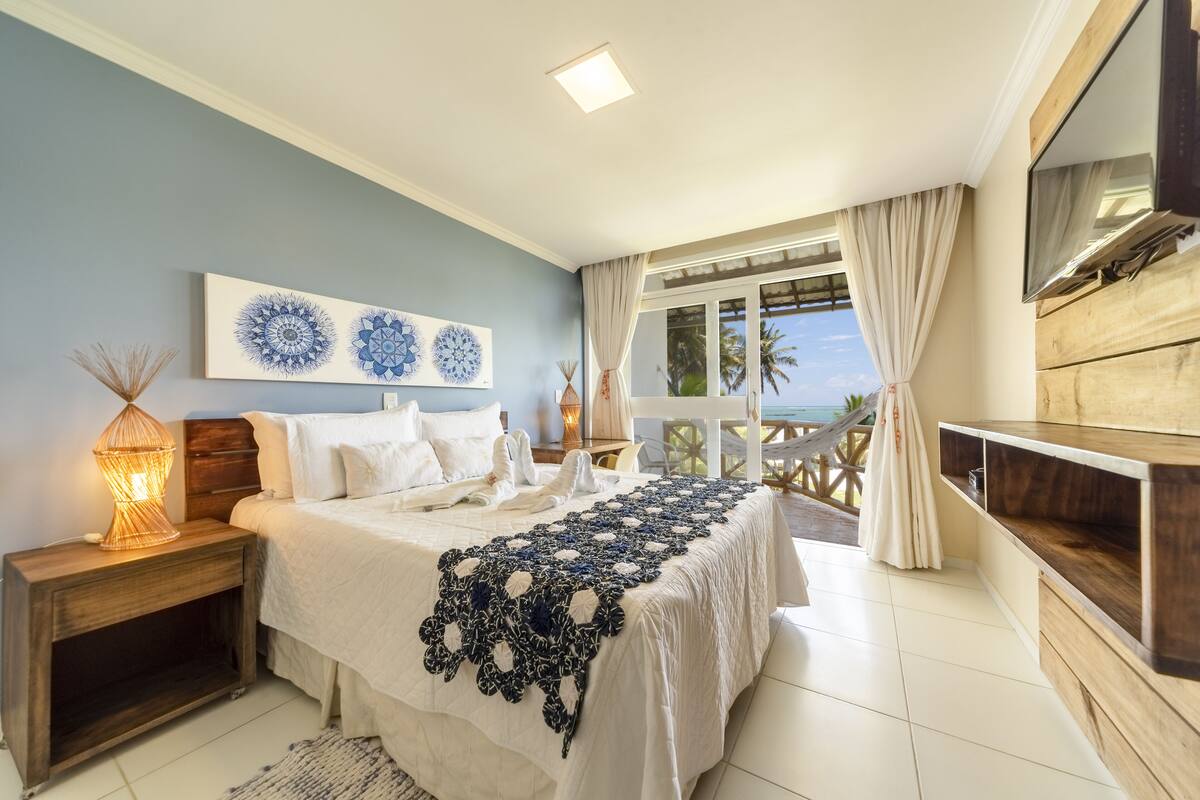 Ein Schlafzimmer mit Bett, Nachttisch und Blick ins Freie.