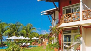 Een resort met een zwembad, terras en weelderige begroeiing.