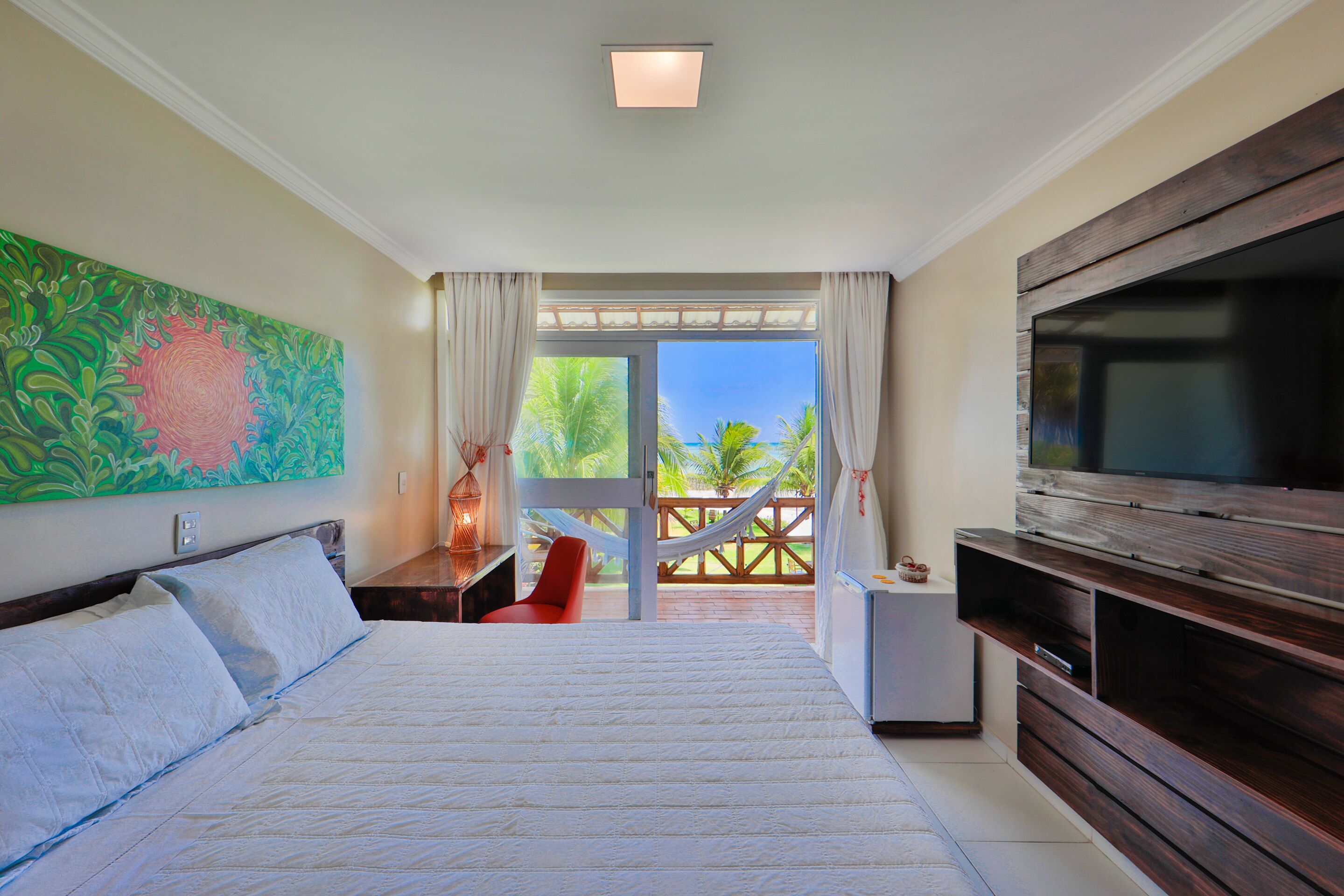 A bedroom with a large bed, a TV, and a view of the outdoors.
