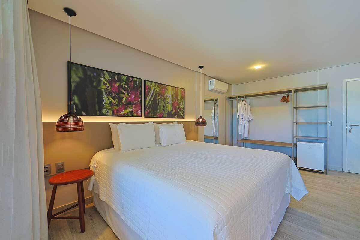 Ein modernes Hotelzimmer mit einem großen Bett, einem Kleiderschrank und einer Hängeleuchte.