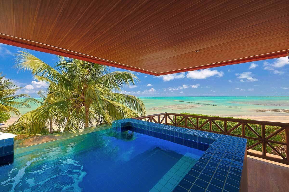 Ein Pool mit Holzterrasse und Blick auf Strand und Meer.