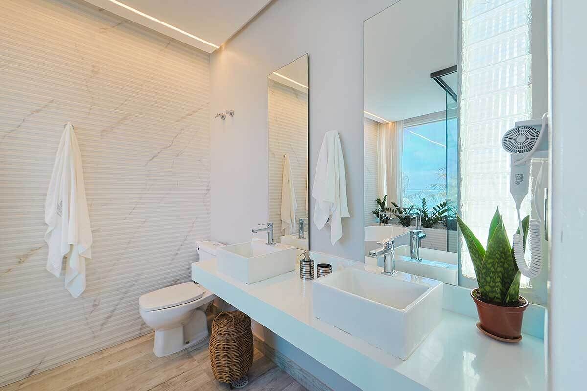 A modern bathroom with a white vanity, two sinks, a toilet, and a large mirror.