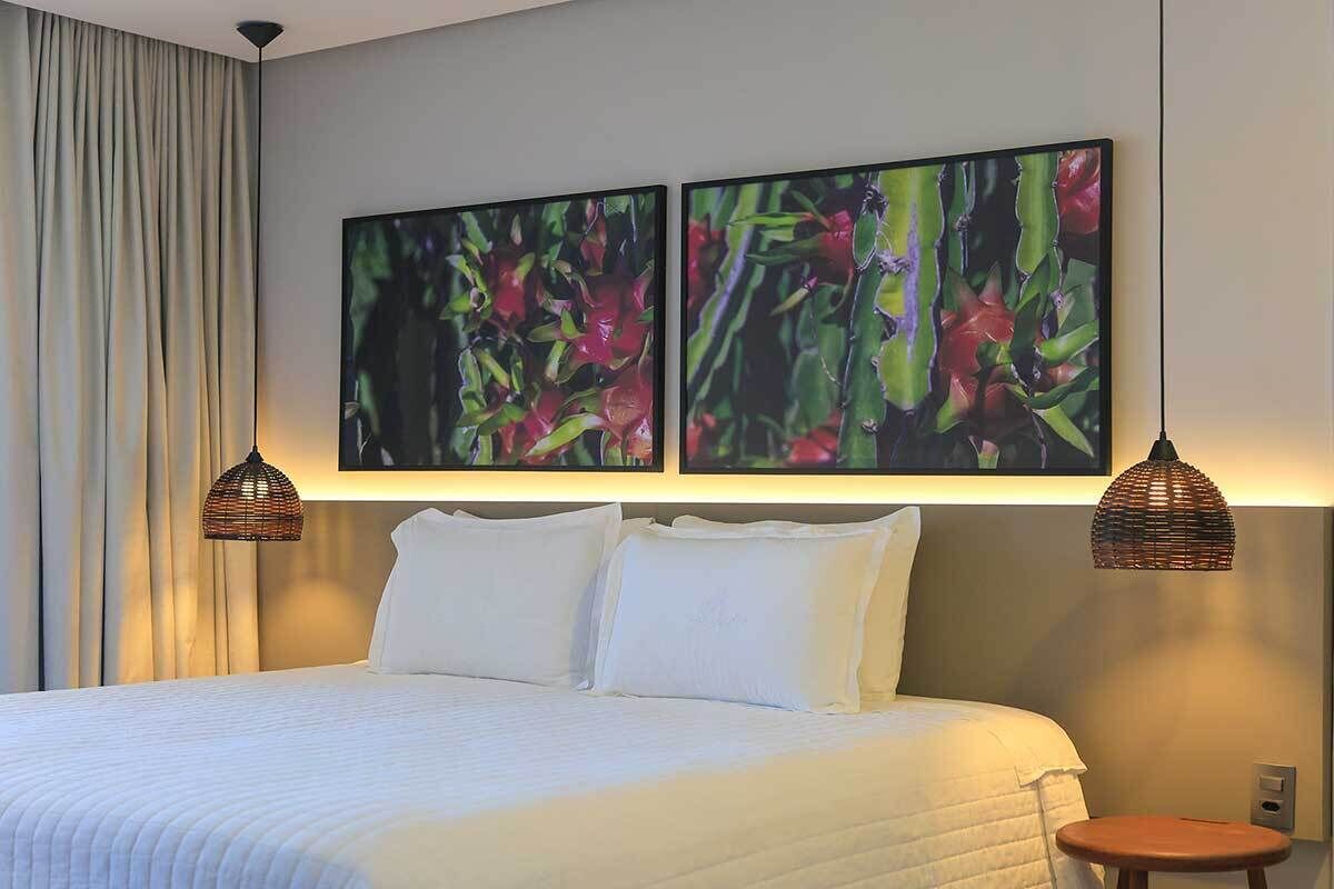 A hotel room with a large bed, two wall-mounted lamps, and two framed floral paintings.
