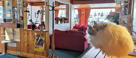 A cozy room with a wooden ceiling, a red sofa, a wooden desk, and a glass door with a poster.