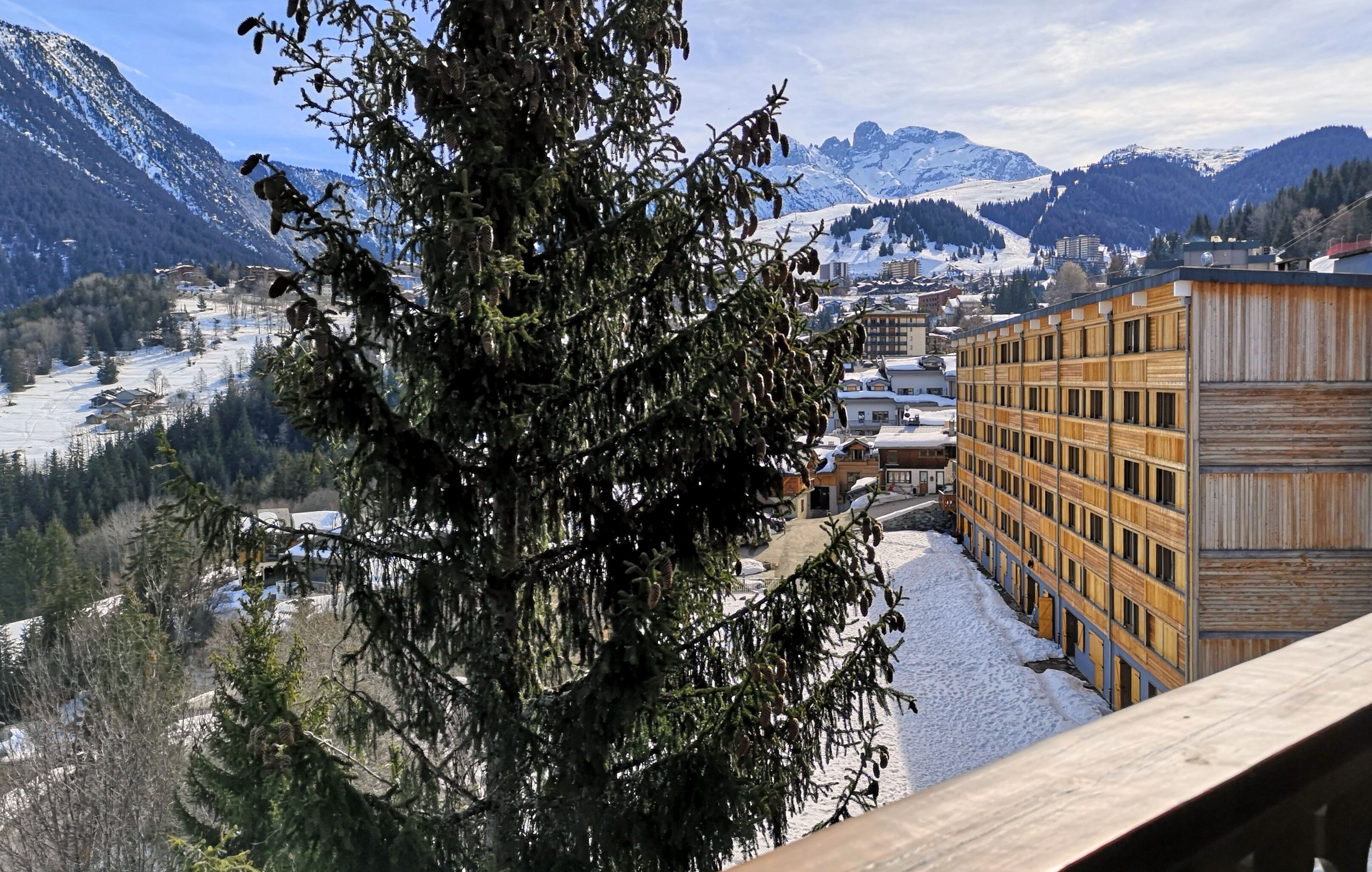 A building with a wooden facade, a snow-covered landscape, and mountains in the background.
