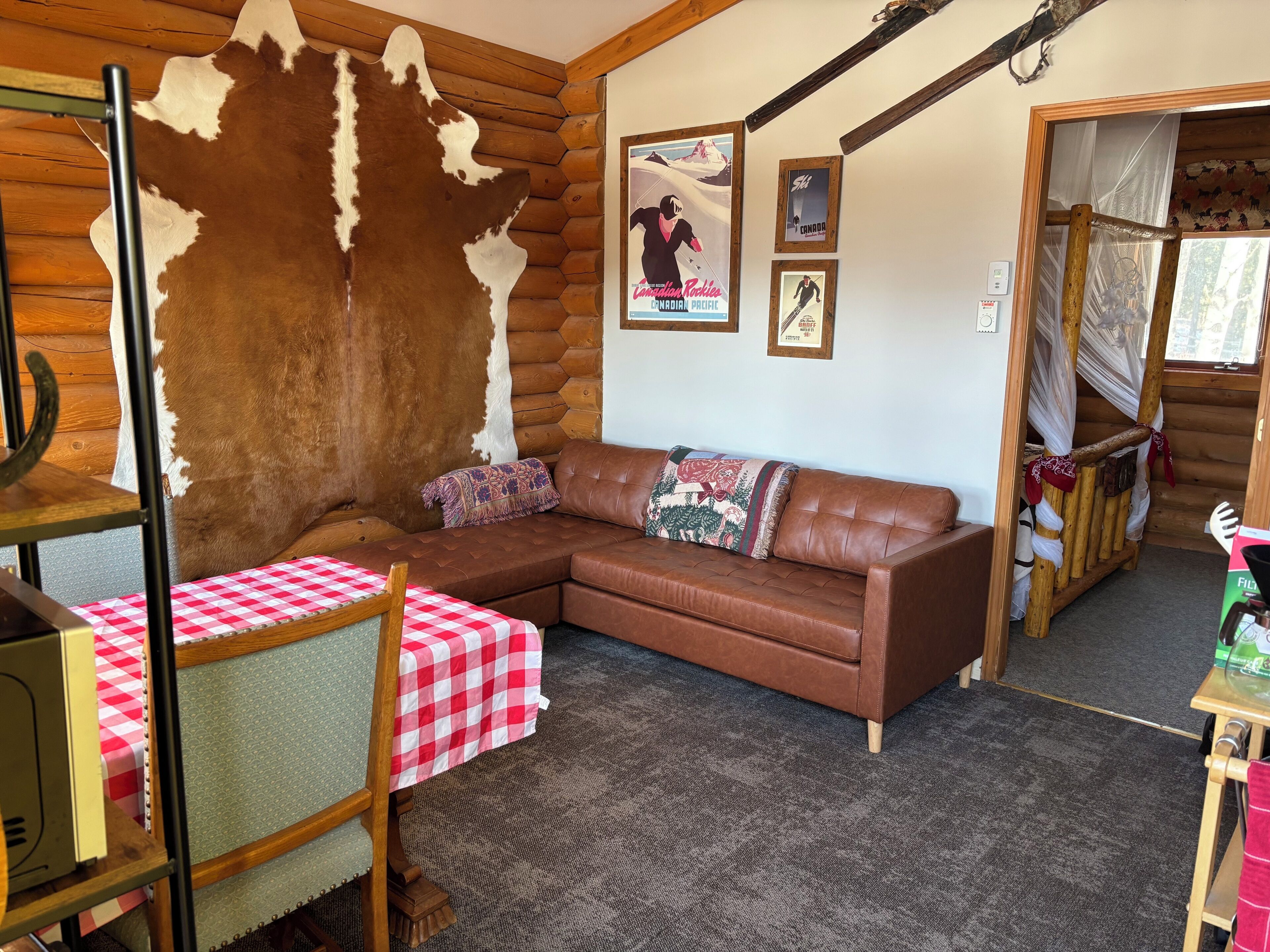 Un intérieur de chalet chaleureux avec un canapé en cuir marron, une table à carreaux et un grand mur recouvert de fourrure.