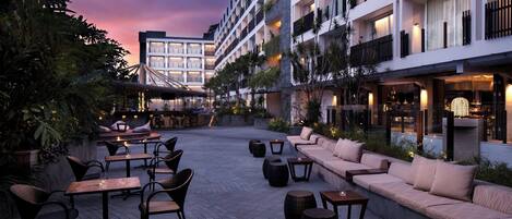 An outdoor patio area with seating arrangements, tables, and a pool.