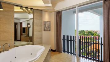 Un baño moderno con una bañera grande, un espejo y vistas a un balcón con barandilla.