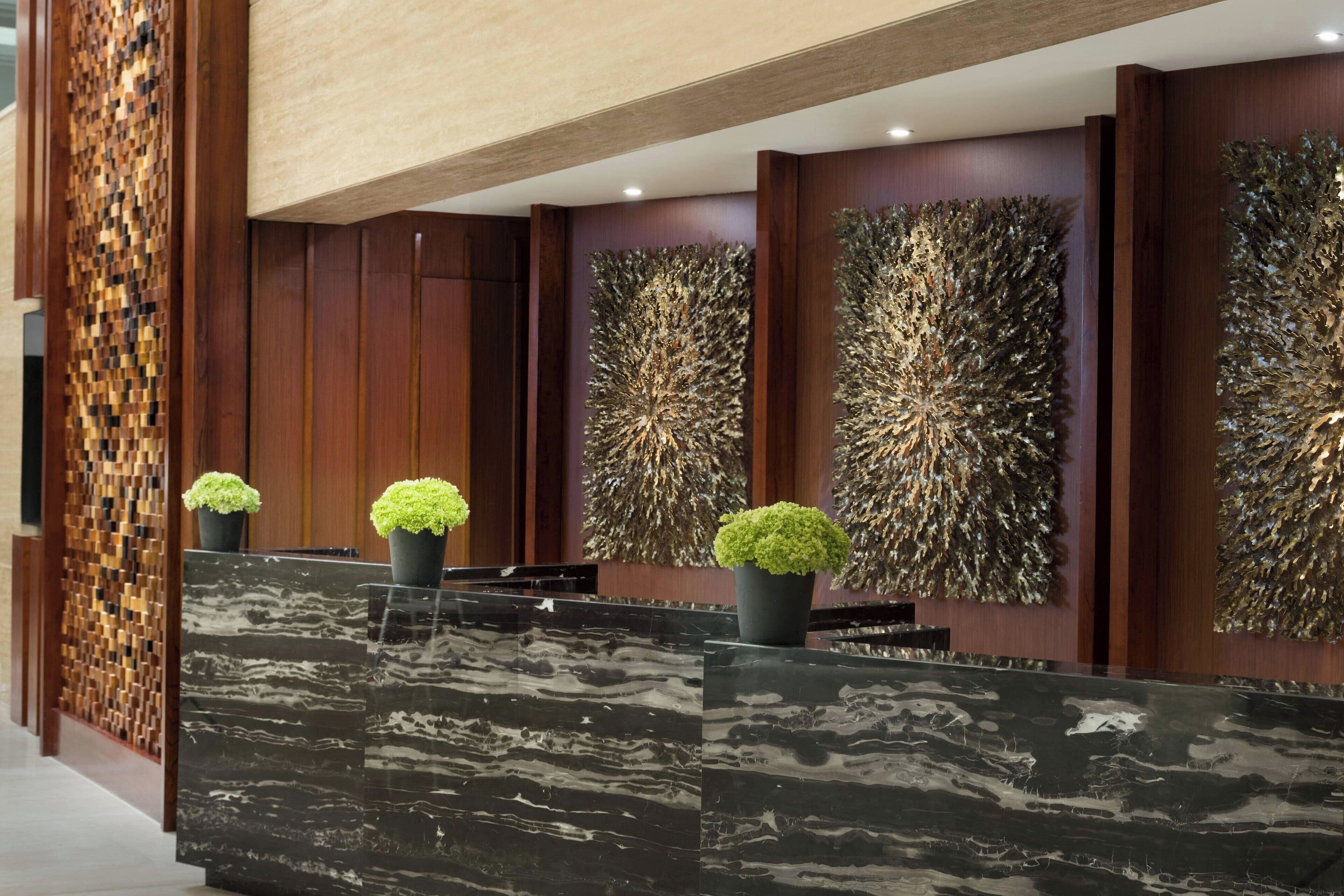 A reception area with a marble reception desk, potted plants, and abstract wall art.