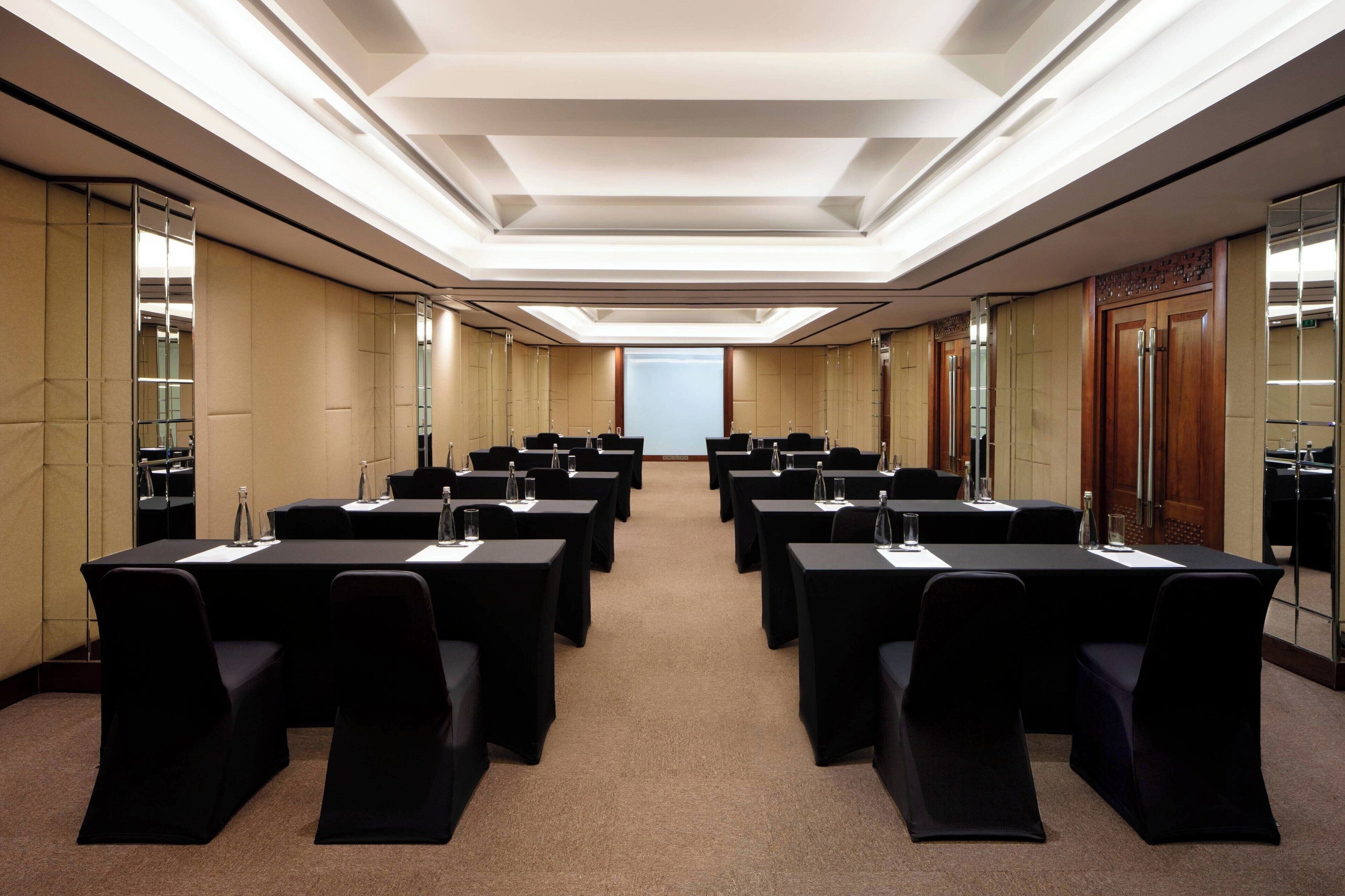 A conference room with multiple tables and chairs, equipped with water bottles and nameplates.