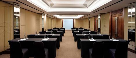 A conference room with multiple tables and chairs, equipped with water bottles and nameplates.