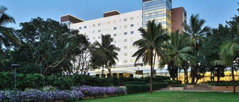 A multi-story hotel with a prominent 'Fairfield Marriott' sign, surrounded by lush greenery and palm trees.