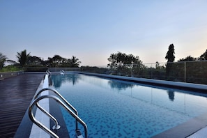 Relax by the pool surrounded by lush trees and a serene atmosphere.
