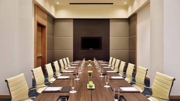 A conference room with a long table, chairs, a TV screen, and a floral centerpiece.