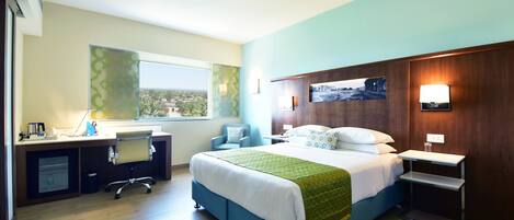 Habitación de hotel con cama, escritorio, silla y vistas al exterior.