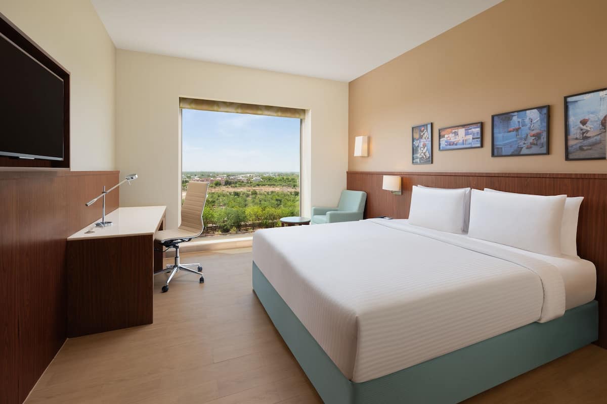 Una habitación de hotel con una cama grande, un escritorio, una silla y un televisor.