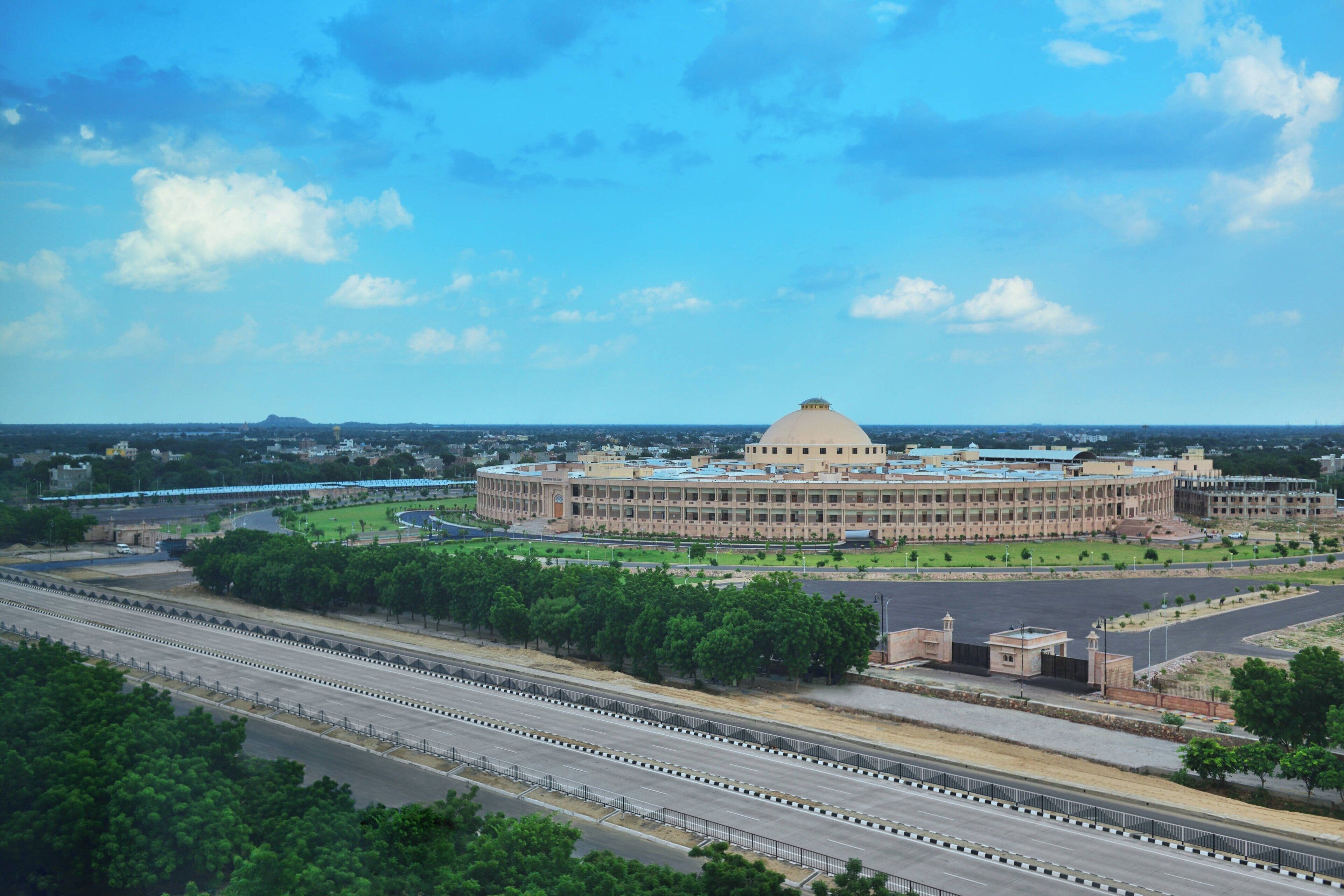 A large, circular building with a dome, surrounded by a well-maintained park and multiple roads.